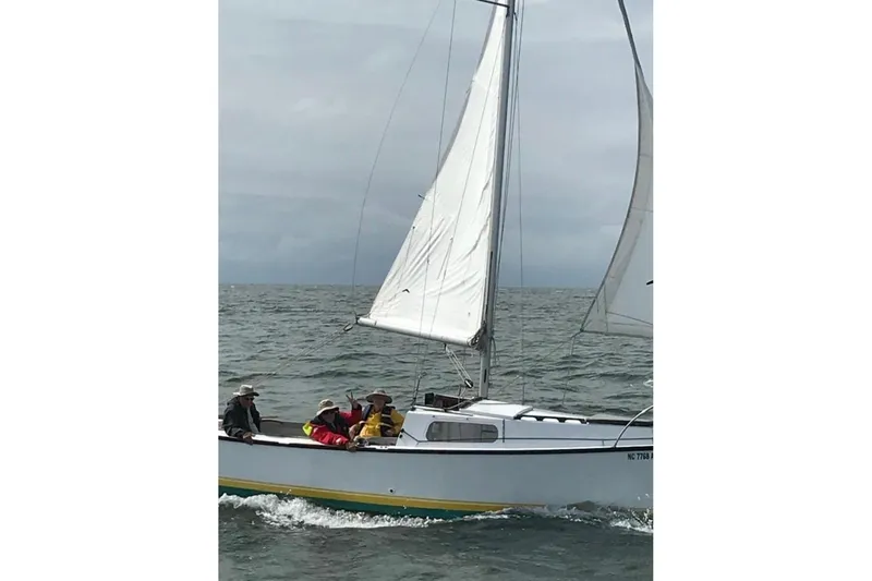 Slide: The Image of 1976 Custom Wooden Sloop for sale at McCotters Marina, on trailer, forest background. - 2