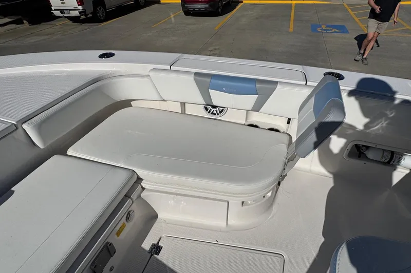 Slide: The Image of 2023 Robalo 266 Cayman boat interior with cushioned seating in a parking lot. - 17