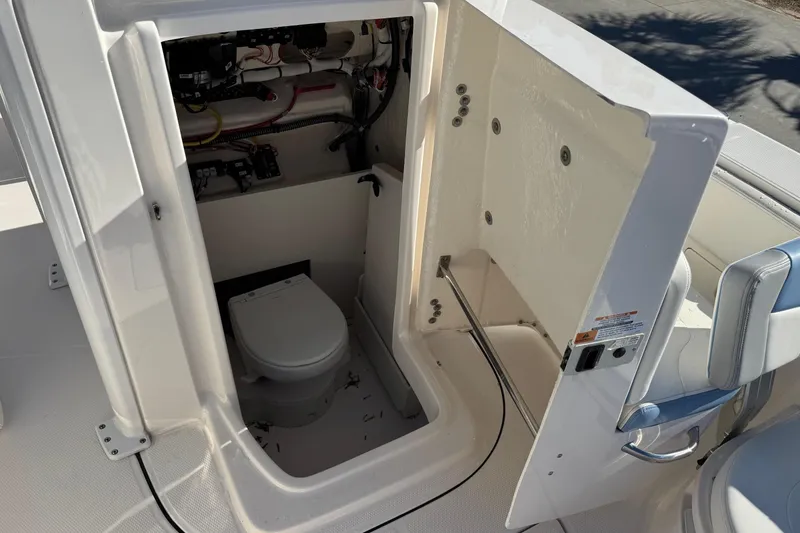 Slide: The Image of 2023 Robalo 266 Cayman boat interior with open compartment and toilet. - 21