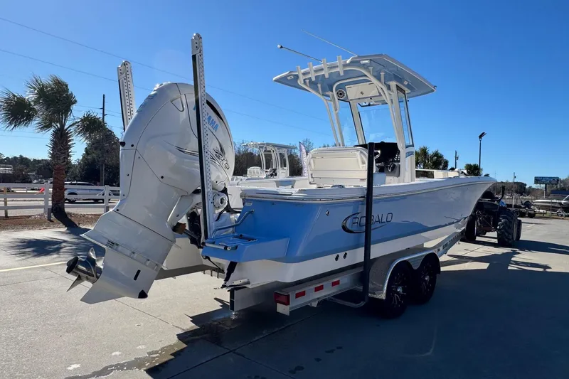 Slide: The Image of 2023 Robalo 266 Cayman boat on trailer, featuring dual engines and T-top, parked outdoors. - 4