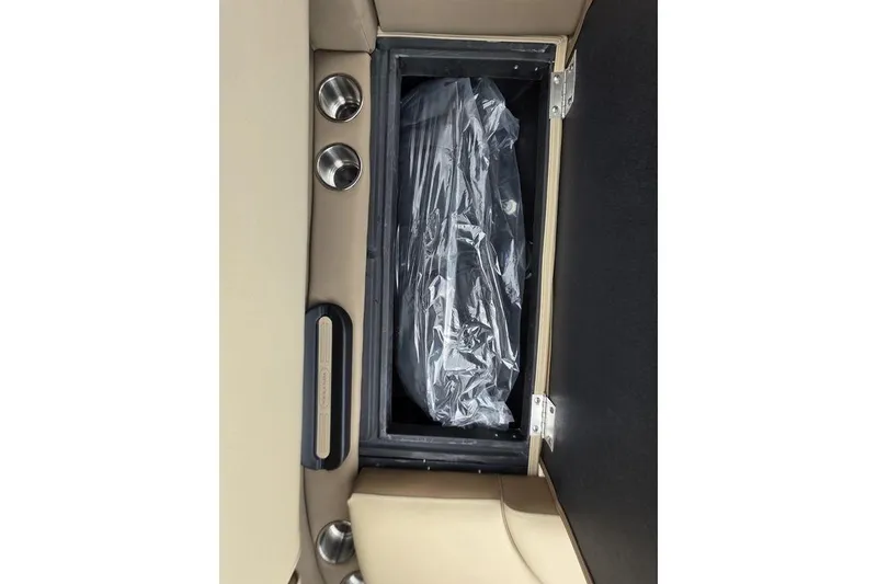 Slide: The Image of Open storage compartment in 2026 Veranda VR22RC Tri-Toon boat, featuring beige seating and cup holders. - 30