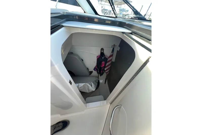 Slide: The Image of 2024 Pursuit DC 326 Dual Console interior storage compartment with life jacket and American flag. - 14