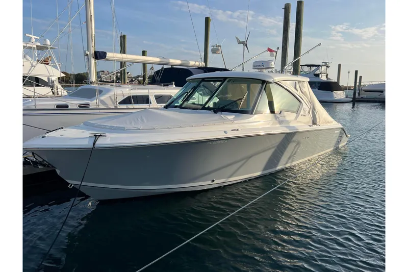 Slide: The Image of 2024 Pursuit DC 326 Dual Console boat docked in marina, calm water, clear sky. - 2