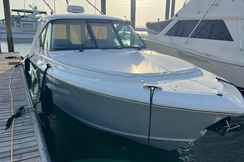 Slide: The Image of 2024 Pursuit DC 326 Dual Console boat docked at marina, covered and ready for adventure. - 3