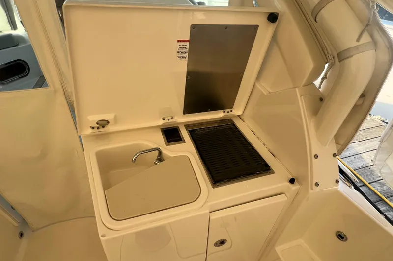 Slide: The Image of 2024 Pursuit DC 326 Dual Console boat interior with sink and grill station. - 7