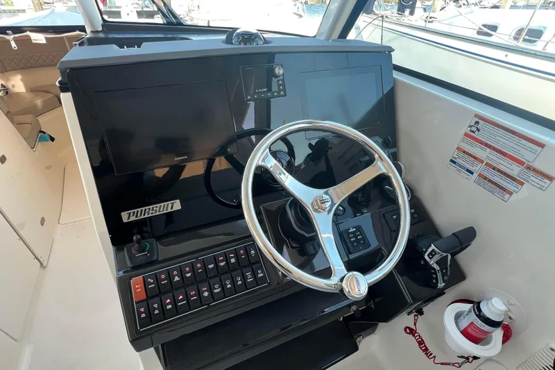 Slide: The Image of 2024 Pursuit DC 326 Dual Console helm with steering wheel, controls, and navigation screens. - 9