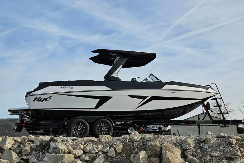 Slide: The Image of 2026 Tigé 24RZX boat on trailer, sleek design, parked on rocky terrain. - 13