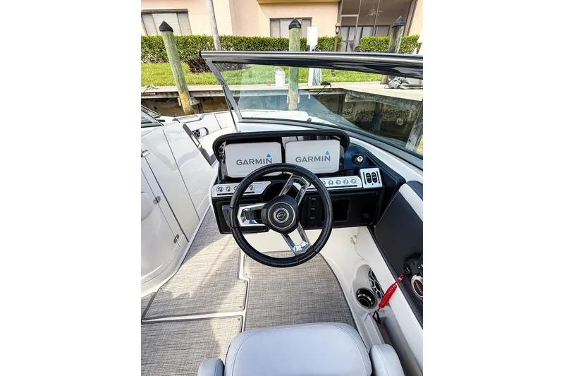 Slide: The Image of 2023 Crownline 270 XSS boat docked in marina, featuring sleek design and Mercury engine. - 2