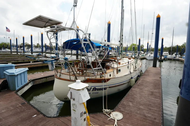 The Image of 1983 Tayana 37 sailboat docked at marina with blue and white accents. - 0