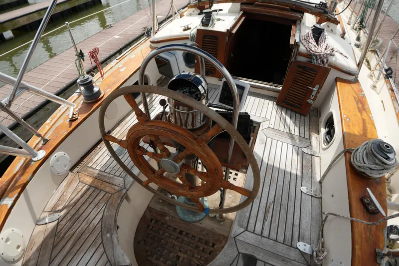 Slide: The Image of Cockpit of 1983 Tayana 37 sailboat with wooden wheel and nautical equipment. - 11