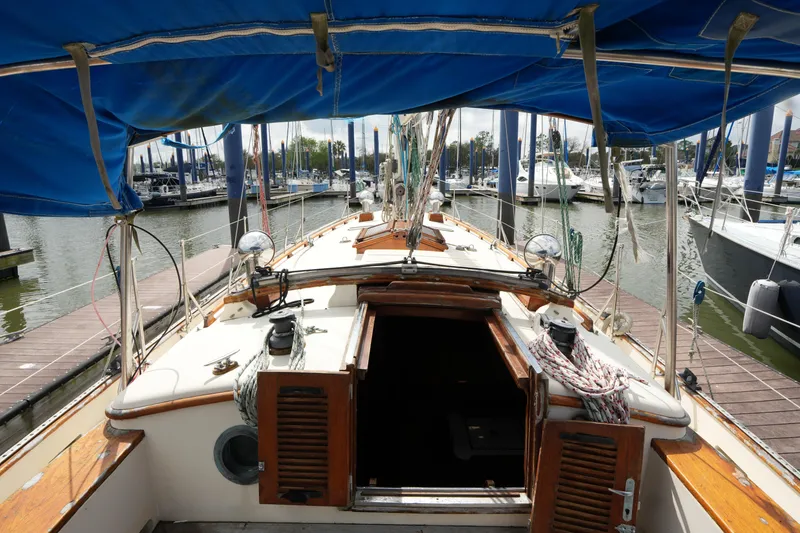 Slide: The Image of 1983 Tayana 37 sailboat docked at marina, featuring wooden deck and blue canopy. - 12