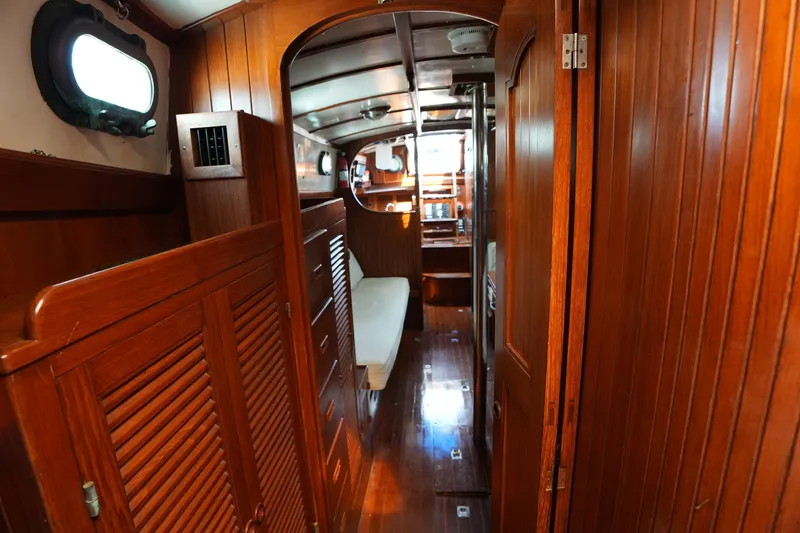 Slide: The Image of Interior of 1983 Tayana 37 sailboat with polished wood paneling and cozy seating area. - 15