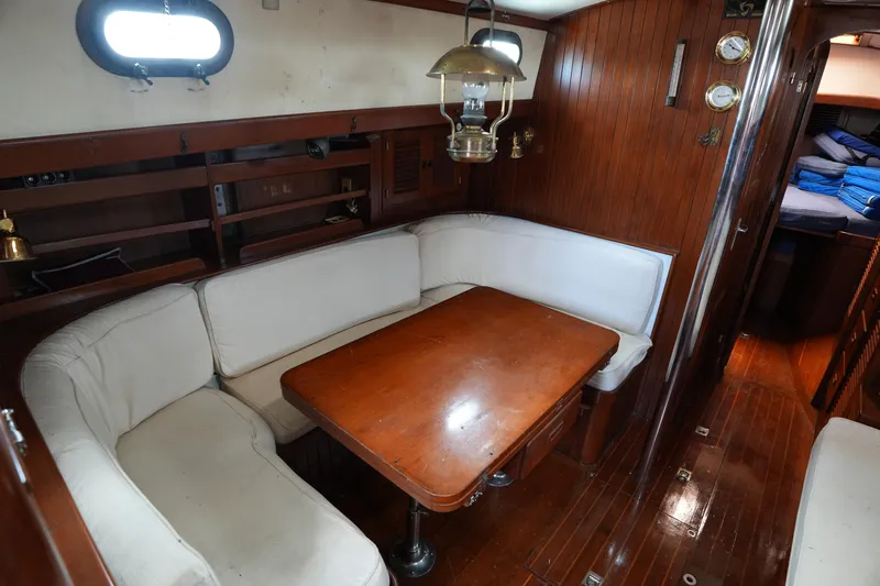 Slide: The Image of Interior of 1983 Tayana 37 sailboat with wooden dining area and white cushions. - 19