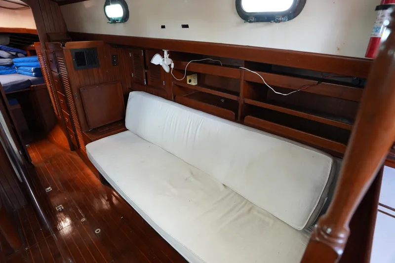 Slide: The Image of Interior of 1983 Tayana 37 sailboat with wooden flooring and white cushioned seating. - 20