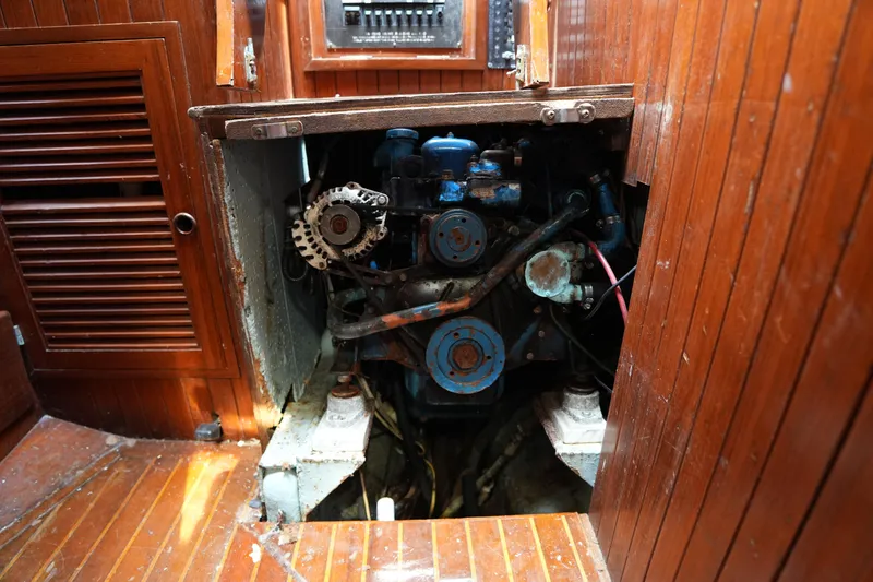 Slide: The Image of Engine compartment of a 1983 Tayana 37 sailboat, showcasing wooden interior and mechanical components. - 26