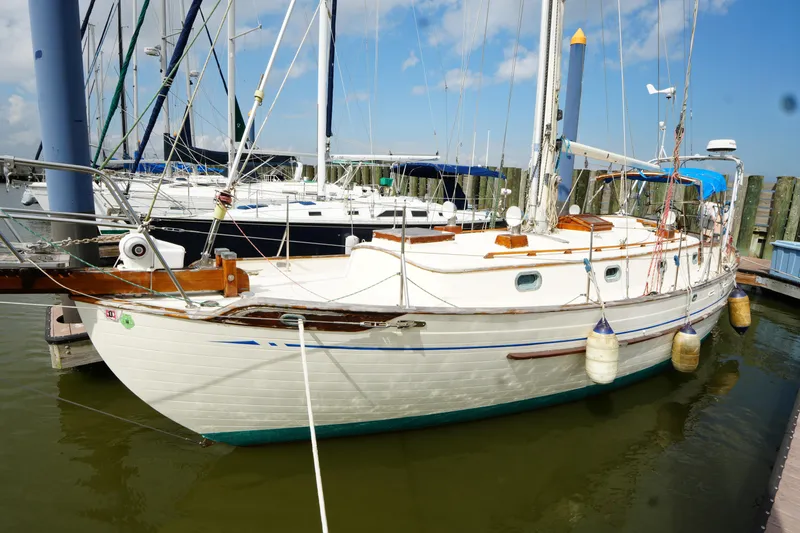 Slide: The Image of 1983 Tayana 37 sailboat docked at marina, surrounded by other boats. - 4