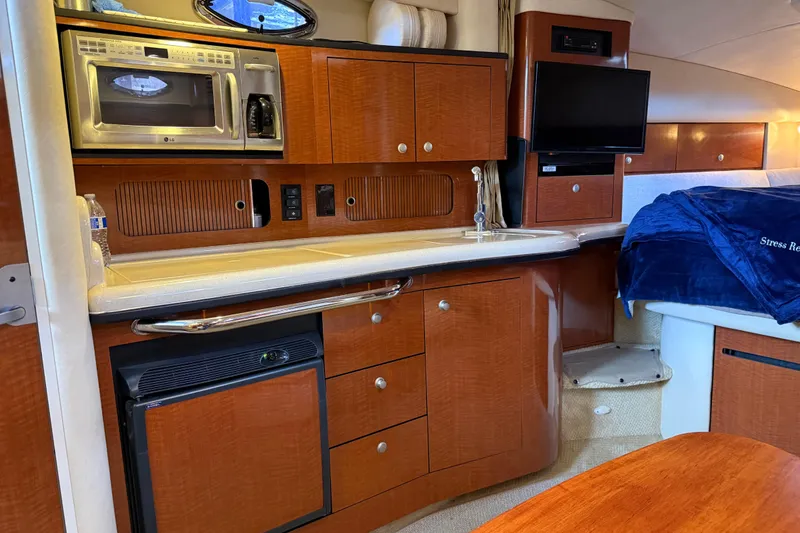 Slide: The Image of 2005 Sea Ray Sundancer 320 interior with kitchenette, microwave, TV, and cozy sleeping area. - 26