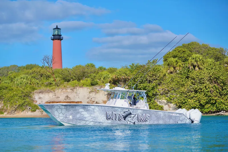 Slide: The Image of 2023 SeaHunter 41 CTS boat near lighthouse, vibrant blue water, lush greenery. - 1