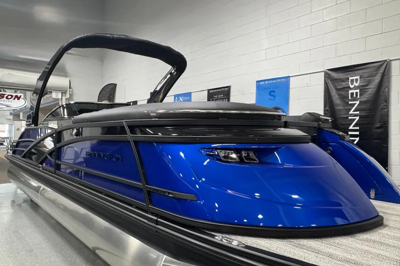 Slide: The Image of 2026 Bennington 25 QSBWASE pontoon boat in showroom, featuring sleek blue design and modern amenities. - 2