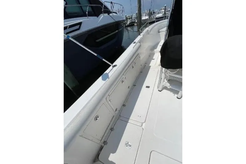 Slide: The Image of 2004 Century 3200 Center Console boat docked, showcasing side deck and storage compartments. - 17