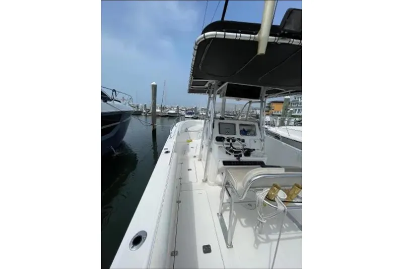 Slide: The Image of 2004 Century 3200 Center Console boat docked at marina, featuring spacious deck and control panel. - 52