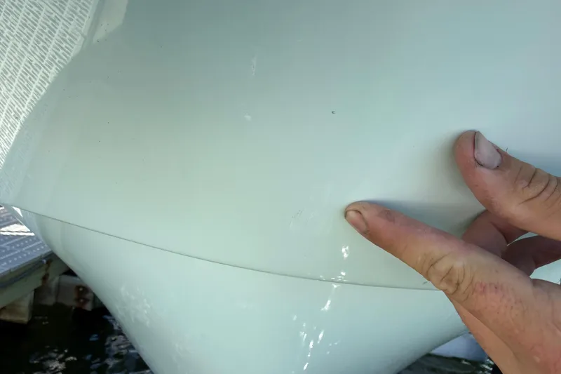 Slide: The Image of Close-up of 2023 Andros Tarpon 26 boat hull with a person inspecting the surface. - 83