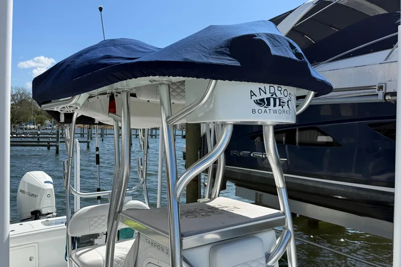 Slide: The Image of 2023 Andros Tarpon 26 boat with blue canopy and sleek design at a marina. - 12