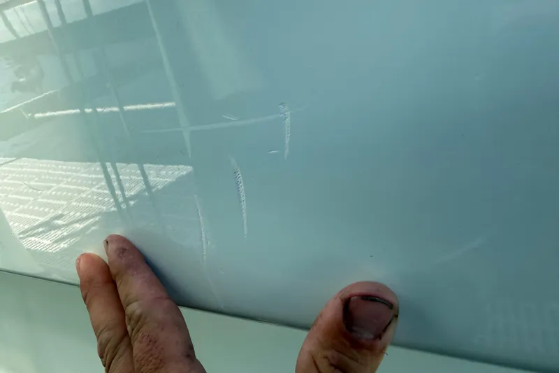 Slide: The Image of 2023 Andros Tarpon 26 boat hull with visible scratches and hand for scale. - 82