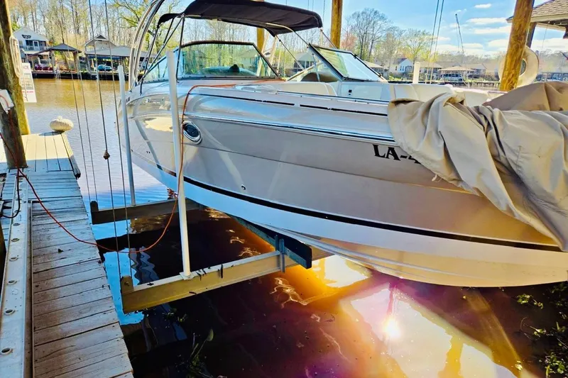 Slide: The Image of 2007 Four Winns 310 Horizon boat docked, partially covered, reflecting sunlight on water. - 2
