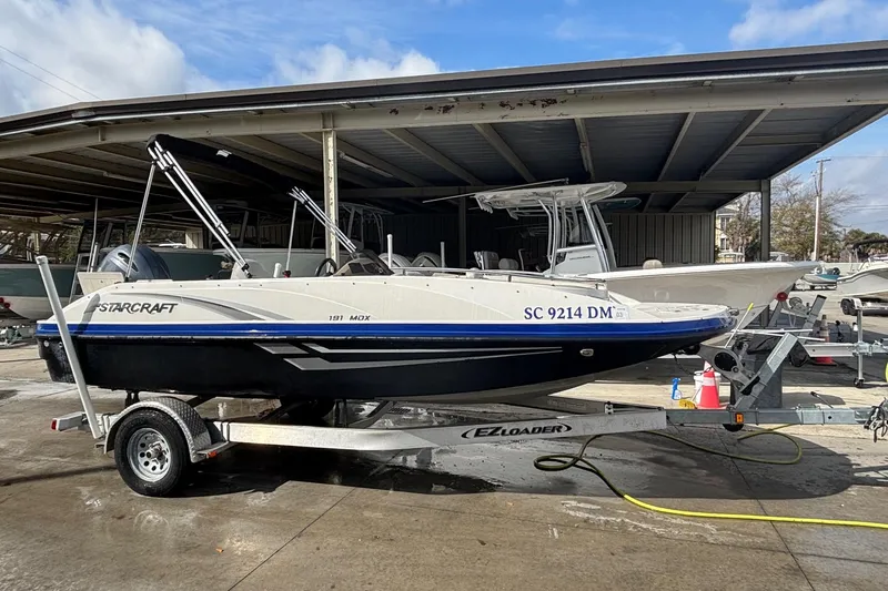 Slide: The Image of 2019 Starcraft MDX 191 O/B boat on trailer in marina setting. - 15
