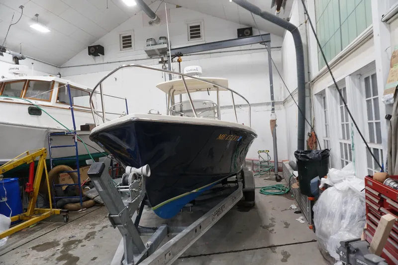 Slide: The Image of 2003 Padebco 23 boat on trailer in a garage, surrounded by equipment. - 13