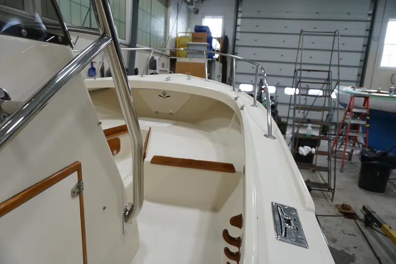 Slide: The Image of 2003 Padebco 23 boat interior in a workshop, featuring wooden accents and stainless steel railings. - 8