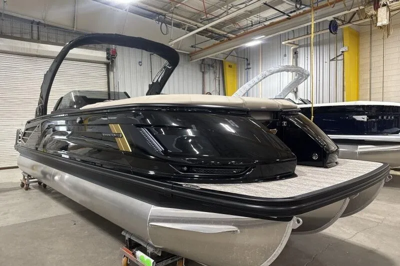 Slide: The Image of 2026 Bennington 25 QXSBWASF pontoon boat in a showroom, sleek black design. - 2
