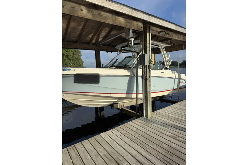 Slide: The Image of 2022 Boston Boatworks Vantage 240 docked under wooden shelter. - 1