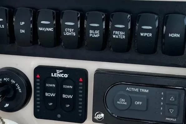 Slide: The Image of Control panel of 2022 Boston Boatworks Vantage 240 with switches and trim controls. - 16