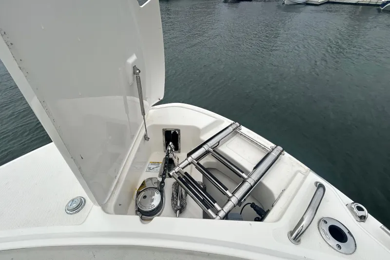 Slide: The Image of 2022 Boston Whaler 240 Vantage boat with open storage compartment and ladder by the water. - 17