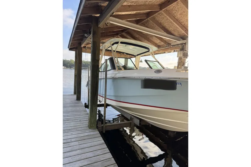 Slide: The Image of 2022 Boston Boatworks Vantage 240 docked under a wooden shelter. - 2
