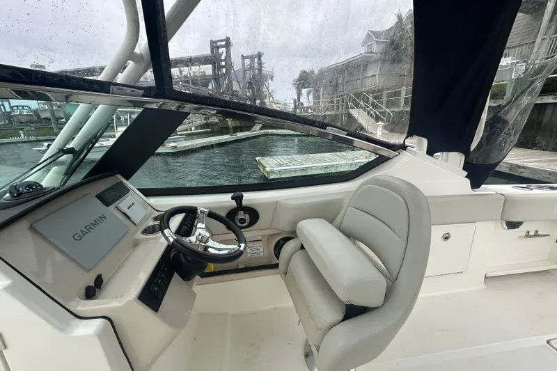 Slide: The Image of 2022 Boston Whaler 240 Vantage helm with Garmin navigation, docked near waterfront homes. - 25