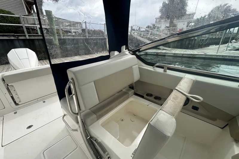 Slide: The Image of 2022 Boston Whaler 240 Vantage boat interior with seating and storage, docked by the water. - 32