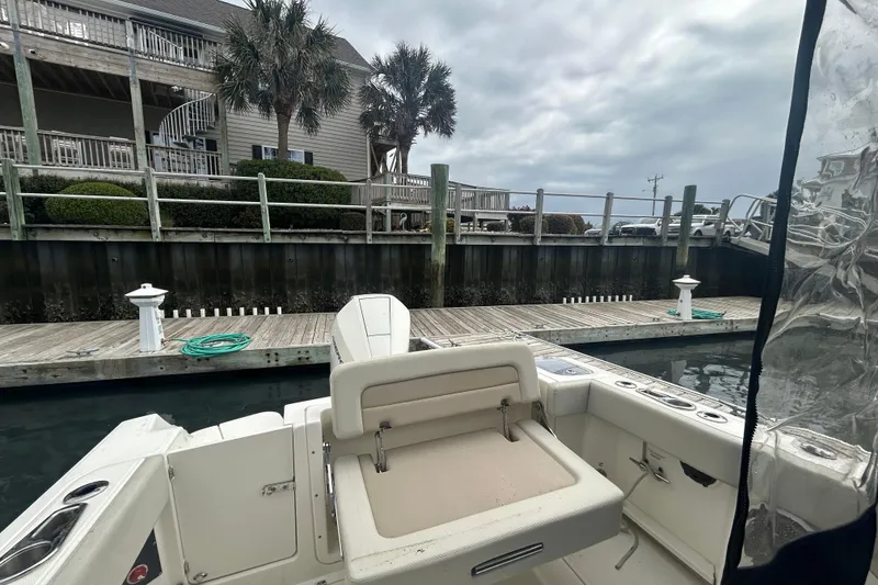 Slide: The Image of Boston Whaler 240 Vantage 2022 docked near waterfront homes under cloudy skies. - 34