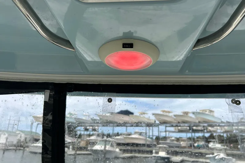 Slide: The Image of Interior view of 2022 Boston Whaler 240 Vantage with red ceiling light and marina background. - 39