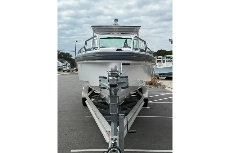 Slide: The Image of 2021 Axopar 28 T-Top boat on trailer, parked in a lot under cloudy skies. - 4