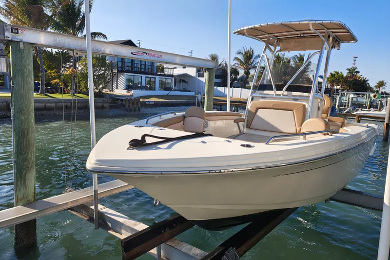 Slide: The Image of 2020 Scout 215 XSF boat on lift, dockside with palm trees and waterfront homes. - 0