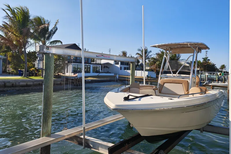 Slide: The Image of 2020 Scout 215 XSF boat docked near waterfront homes and palm trees. - 11