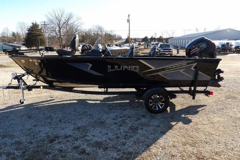 Slide: The Image of 2025 Lund 1775 Adventure SS boat on trailer, parked outdoors in a sunny setting. - 3