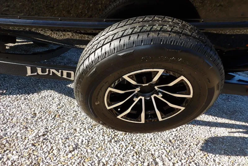 Slide: The Image of 2025 Lund 1775 Adventure SS trailer wheel on gravel surface. - 43
