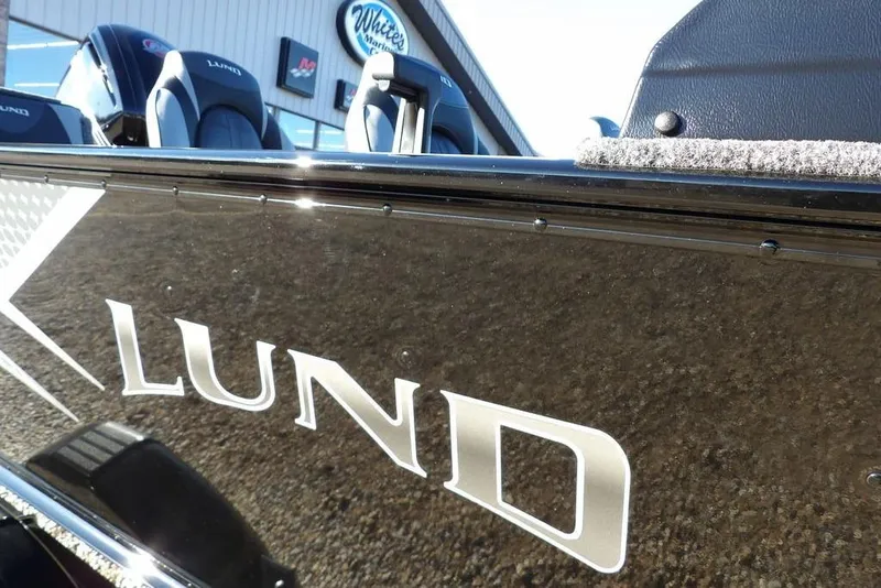 Slide: The Image of 2025 Lund 1775 Adventure SS boat exterior with logo, displayed at a marine dealership. - 46