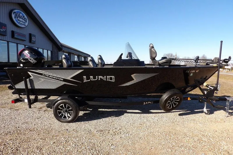 Slide: The Image of 2025 Lund 1775 Adventure SS boat on trailer, parked outside a marine center. - 5