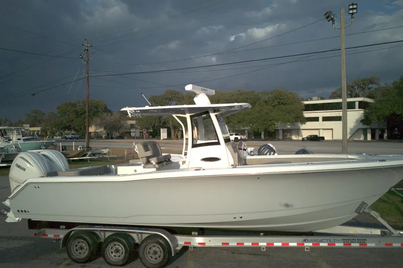 Slide: The Image of 2024 Sea Hunt Gamefish 30 Coffin Box boat on trailer, parked outdoors under cloudy sky. - 1