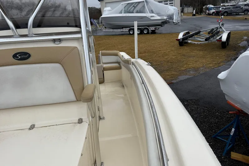 Slide: The Image of 2014 Scout 210 XSF boat interior with beige seating, parked near trailers. - 6